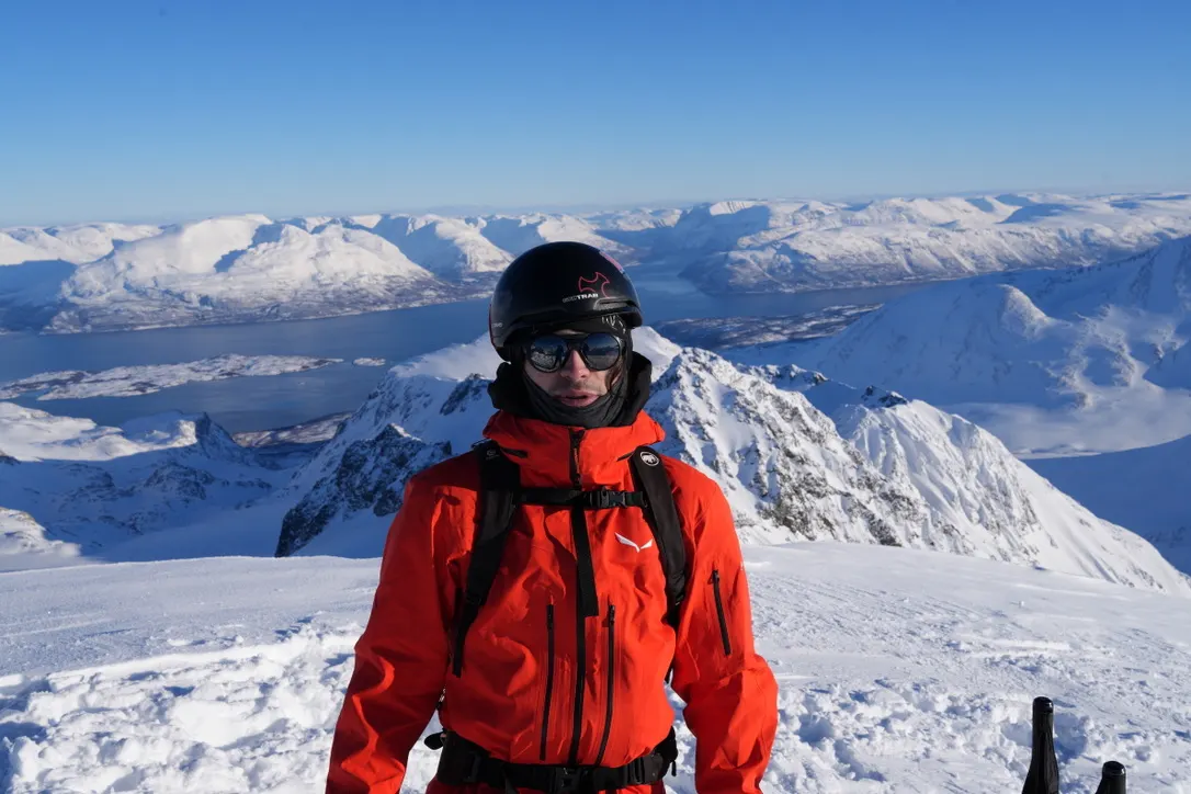 Skier on a snowy summit above a fjord